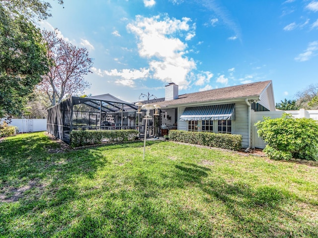 back of house with a lanai, a chimney, a yard, and fence