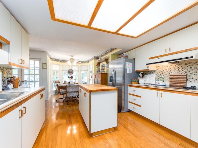2893 Turtle Ter, Palm Harbor, FL 34683 - kitchen with under cabinet range hood, stainless steel fridge, butcher block countertops, light wood-style flooring, and white cabinets