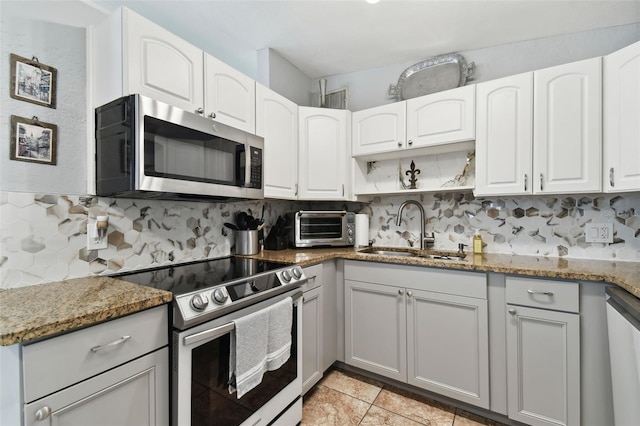 kitchen with white cabinetry, sink, dark stone countertops, backsplash, and stainless steel appliances