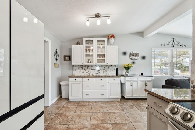 kitchen featuring light tile patterned floors, stove, tasteful backsplash, lofted ceiling with beams, and white cabinets