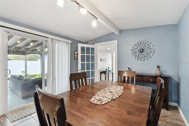 tiled dining room featuring track lighting and lofted ceiling with beams