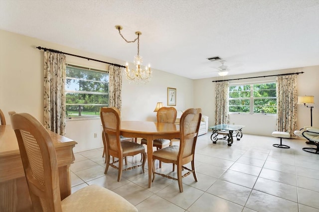 dining area featuring ceiling fan with notable chandelier, light tile patterned floors, and a textured ceiling