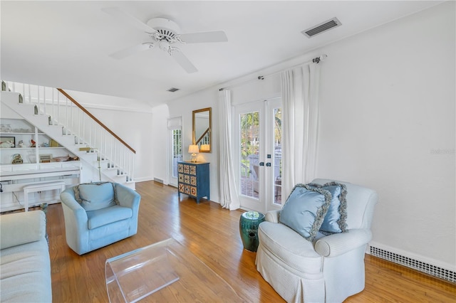 living room featuring wood-type flooring, ceiling fan, and french doors