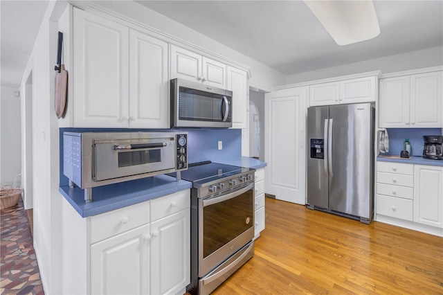 kitchen featuring white cabinetry, light hardwood / wood-style floors, and appliances with stainless steel finishes