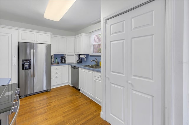 kitchen featuring stainless steel appliances, light hardwood / wood-style floors, sink, and white cabinets