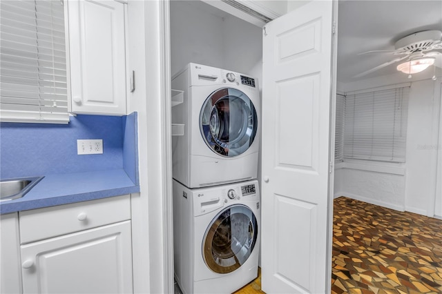 clothes washing area featuring stacked washer and clothes dryer and ceiling fan