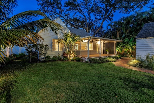 rear view of property featuring a sunroom and a lawn