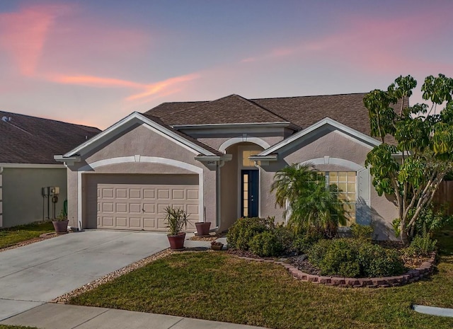 ranch-style house with a garage and a lawn