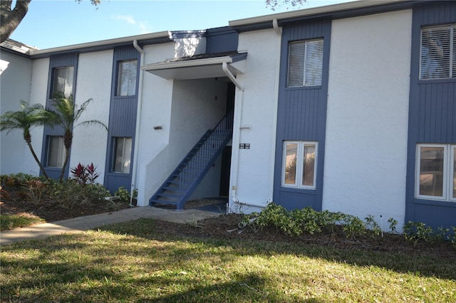 property entrance with a lawn and stucco siding