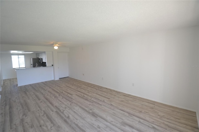 unfurnished living room with light wood finished floors, ceiling fan, and a textured ceiling