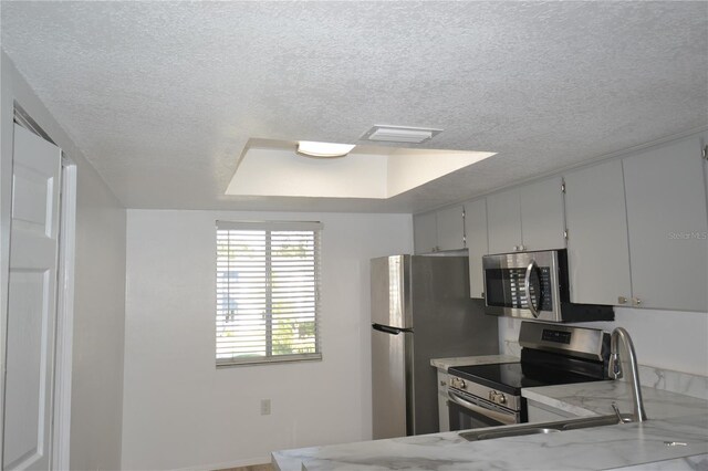 kitchen featuring light stone countertops, visible vents, appliances with stainless steel finishes, and a textured ceiling