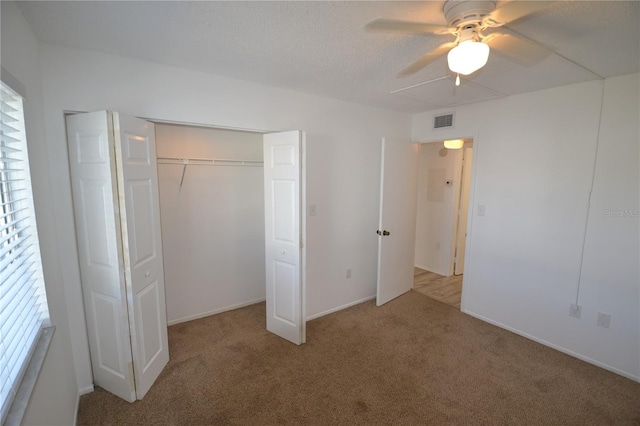 unfurnished bedroom with visible vents, a ceiling fan, a textured ceiling, carpet floors, and a closet