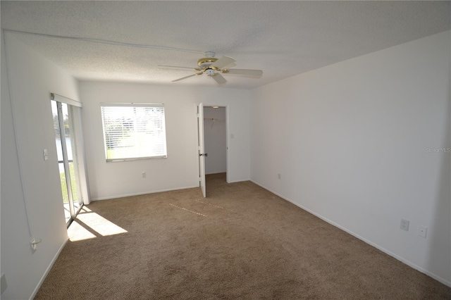 unfurnished bedroom with ceiling fan, a textured ceiling, a spacious closet, and carpet flooring