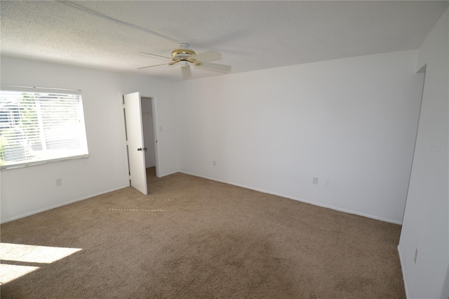 carpeted empty room featuring a textured ceiling, ceiling fan, and baseboards