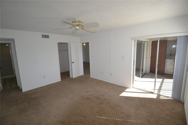 unfurnished bedroom with a textured ceiling, ensuite bathroom, visible vents, carpet, and washer / dryer