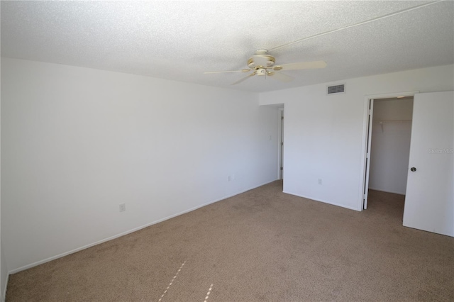 carpeted spare room with a textured ceiling, ceiling fan, and visible vents