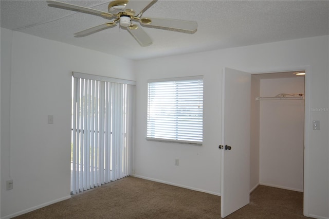 unfurnished bedroom with a textured ceiling, carpet floors, and a ceiling fan