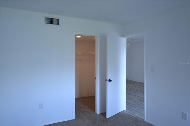 unfurnished bedroom with carpet floors, a closet, visible vents, and a spacious closet