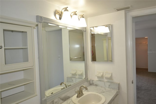 bathroom featuring vanity, visible vents, and a walk in closet