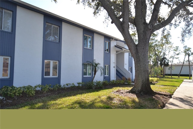 view of side of property featuring a lawn and stucco siding