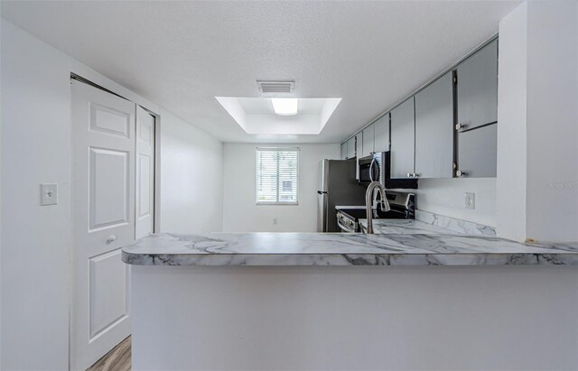 256 Cypress Ln Unit 120, Oldsmar, FL 34677 - kitchen featuring stainless steel appliances, light countertops, light wood-style floors, and a peninsula