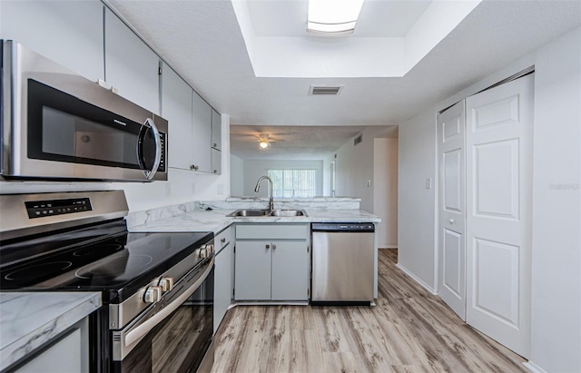 256 Cypress Ln Unit 120, Oldsmar, FL 34677 - kitchen with appliances with stainless steel finishes, a sink, light wood-style floors, a peninsula, and light stone countertops