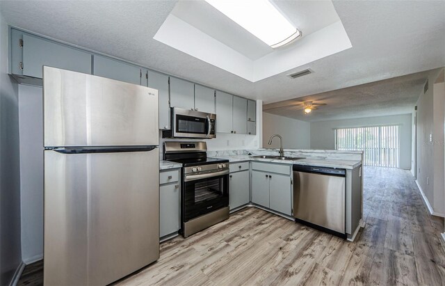 256 Cypress Ln Unit 120, Oldsmar, FL 34677 - kitchen featuring appliances with stainless steel finishes, a sink, a peninsula, and light wood-style flooring