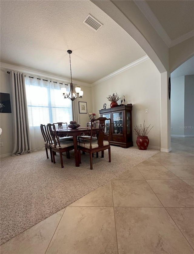 dining room with crown molding, tile patterned floors, a textured ceiling, and a chandelier