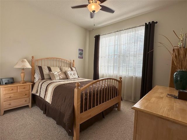 bedroom featuring ceiling fan, light colored carpet, and a textured ceiling