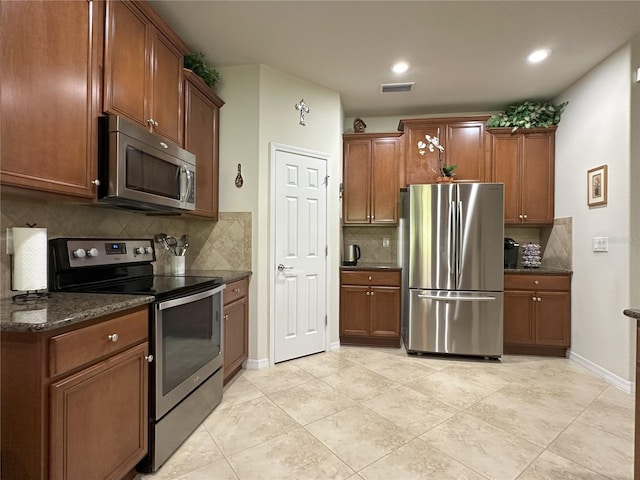 kitchen with stainless steel appliances, dark stone counters, and backsplash