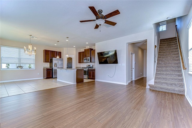 unfurnished living room featuring sink, ceiling fan with notable chandelier, and light wood-type flooring