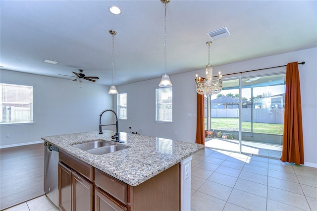 kitchen featuring sink, dishwasher, light stone countertops, an island with sink, and decorative light fixtures