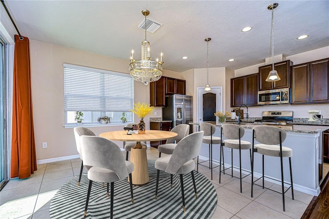 dining space with an inviting chandelier, a textured ceiling, and light tile patterned floors