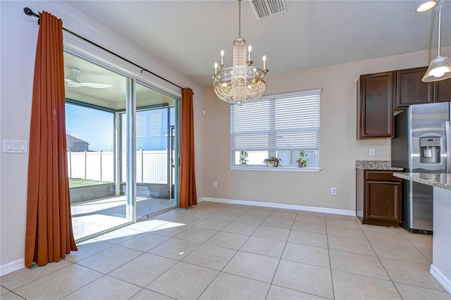 kitchen with light stone counters, light tile patterned floors, decorative light fixtures, and stainless steel refrigerator with ice dispenser