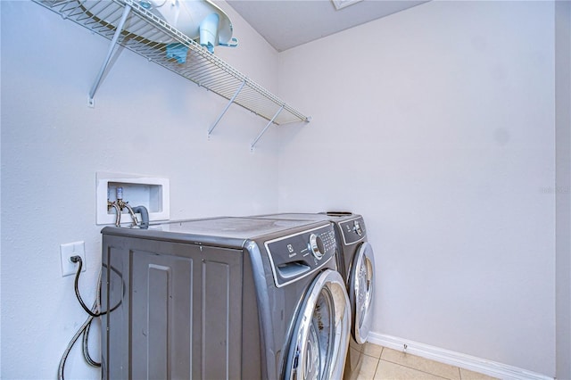 clothes washing area featuring washer and clothes dryer and light tile patterned floors