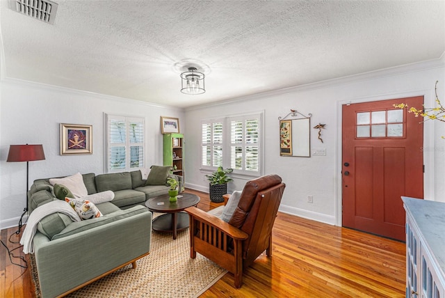 living room featuring ornamental molding, light hardwood / wood-style flooring, and a textured ceiling