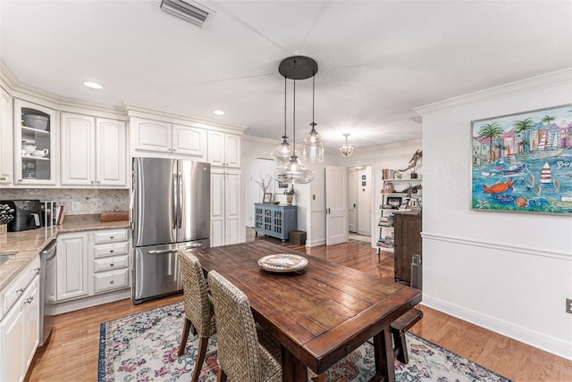 dining area with crown molding and light wood-type flooring