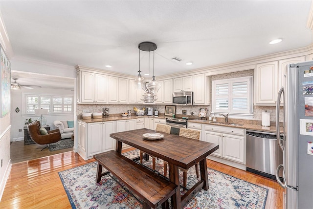 kitchen featuring stainless steel appliances, white cabinetry, sink, and pendant lighting