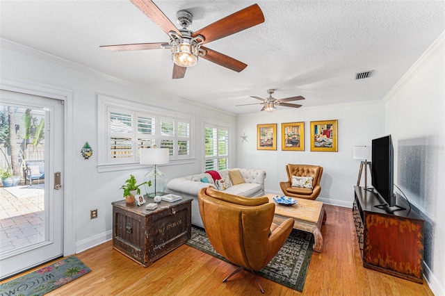 living room with hardwood / wood-style floors, ornamental molding, and a textured ceiling