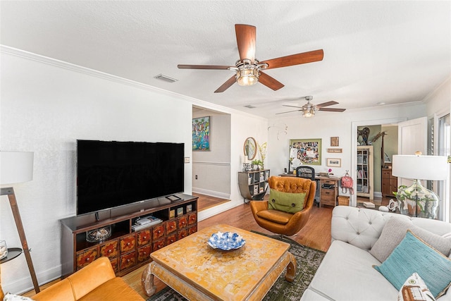 living room with crown molding, wood-type flooring, and a textured ceiling