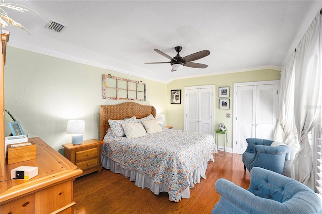 bedroom with multiple closets, ceiling fan, crown molding, and hardwood / wood-style floors