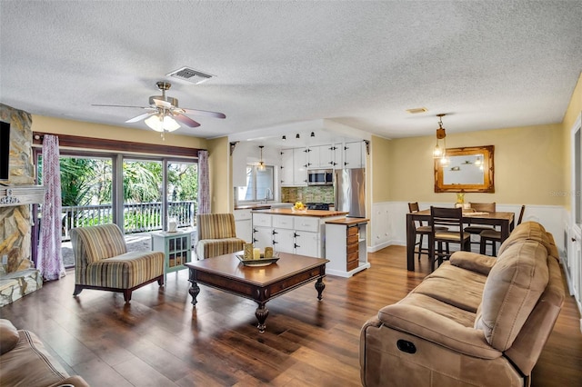 living room with ceiling fan, sink, hardwood / wood-style floors, and a textured ceiling