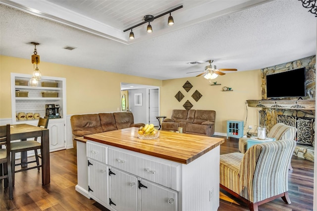 kitchen with butcher block countertops, white cabinetry, dark hardwood / wood-style floors, a textured ceiling, and built in shelves