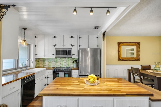 kitchen with hanging light fixtures, black appliances, white cabinets, and a kitchen island