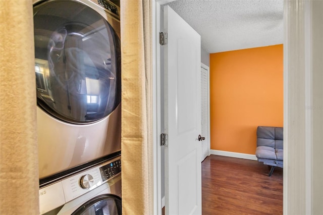 laundry room with dark wood-type flooring, stacked washer / dryer, and a textured ceiling