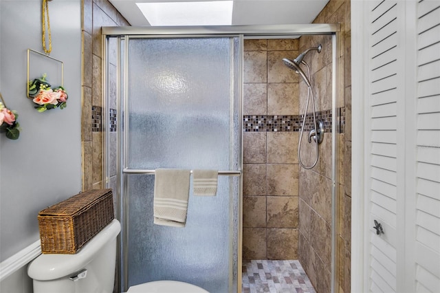 bathroom featuring a shower with door and toilet