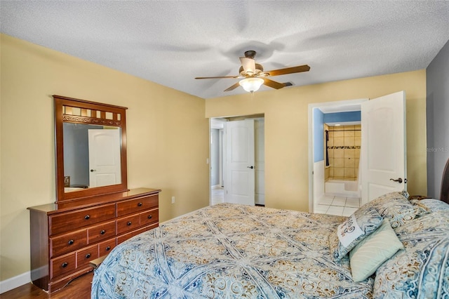 tiled bedroom with ceiling fan, a textured ceiling, and ensuite bath