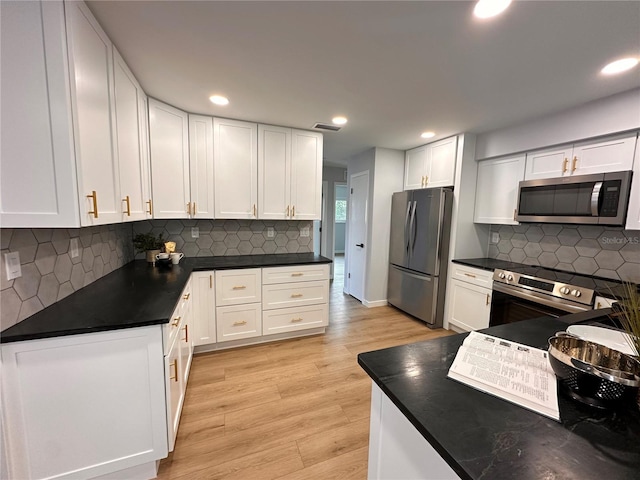 kitchen featuring white cabinetry, stainless steel appliances, light hardwood / wood-style floors, and backsplash