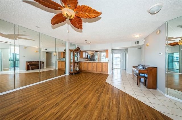 kitchen featuring brown cabinetry, a ceiling fan, open floor plan, a textured ceiling, and wood finished floors