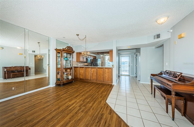 kitchen with an inviting chandelier, visible vents, brown cabinets, and light countertops